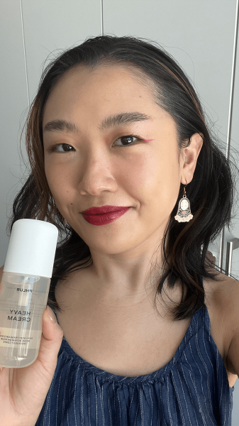 Allure commerce editor Sarah Han holding a bottle of the Phlur Heavy Cream Body Mist